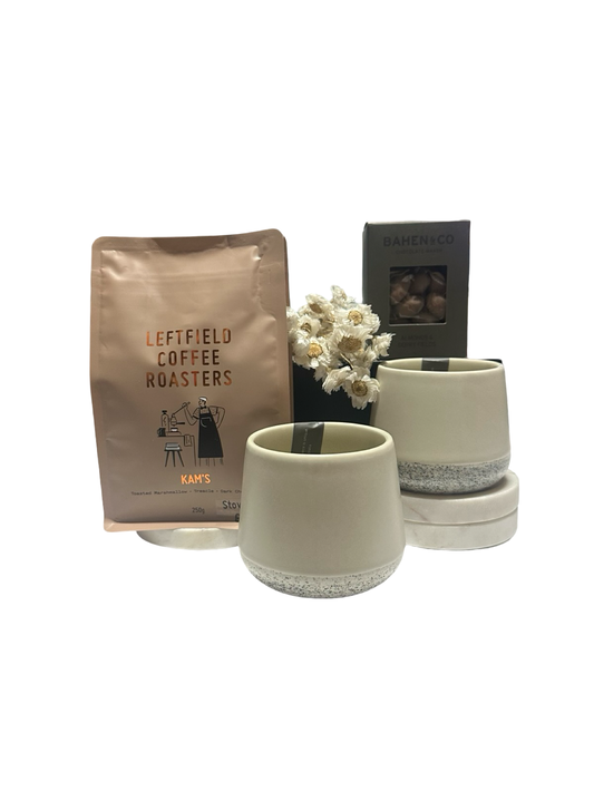 Two ceramic tumblers with a small white flower arrangement and a bag of Leftfield Coffee Roasters on a white background.