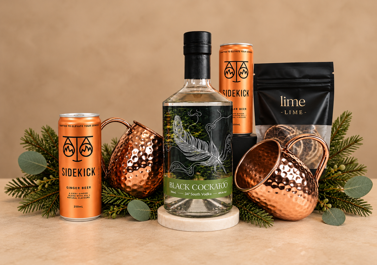 A stylish gift designed for relaxed entertaining and festive celebrations. Featuring premium Black Cockatoo Vodka, Sidekick Ginger Beer, zesty lime and two beautiful hammered copper Moscow Mule mugs — everything needed to create the perfect drink at home.
Presented in a sleek black gift box and finished with luxurious black ribbon and subtle festive touches, this is a fun, sophisticated Christmas gift with a distinctly Australian flavour.