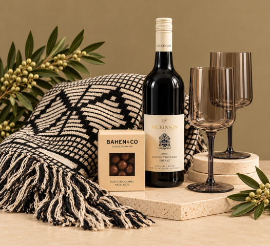 Wine bottle, two wine glasses, gourmet nuts and a blanket on a beige background