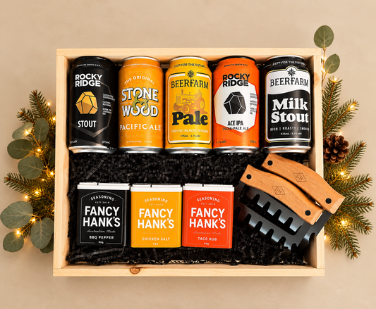 Wooden crate with beers, meat claws and some seasoning in tins on beige background.