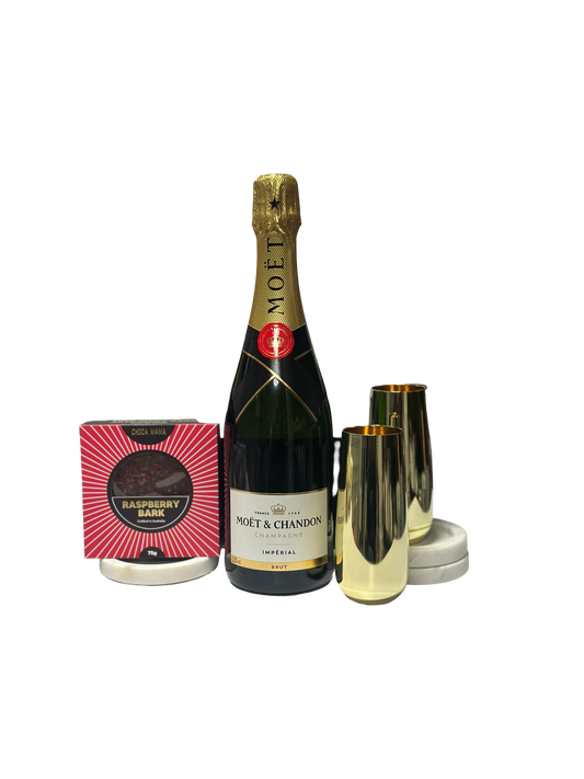 Bottle of Moet & Chandon champagne with two gold flutes and a box on a white background