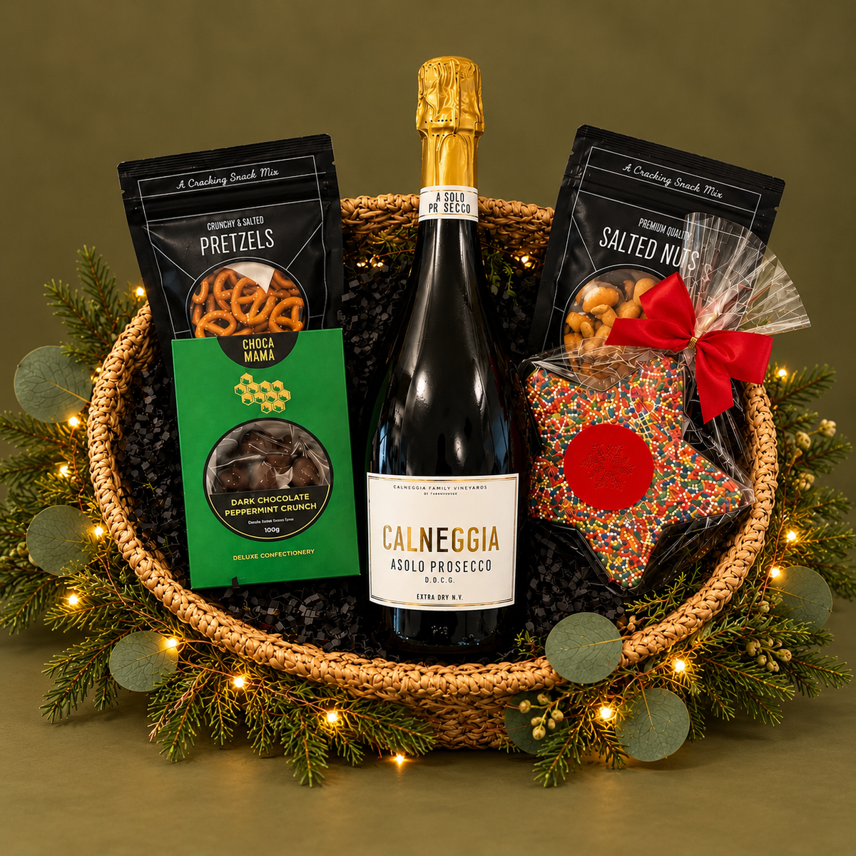 Small basket with sparkling wine and some gourmet treats on beige background with greenery and lights