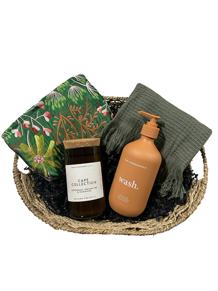 Basket with bath products including a bottle, soap, and towel on a white background