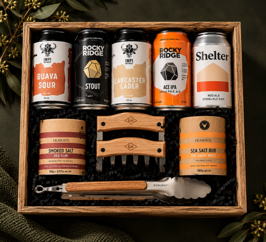 Collection of beer cans, salt rubs and BBQ tools and related items in a box on a white background