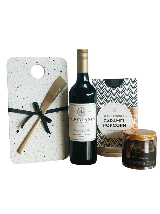 Wine bottle, popcorn, candle, and cutting board with knife on a white background