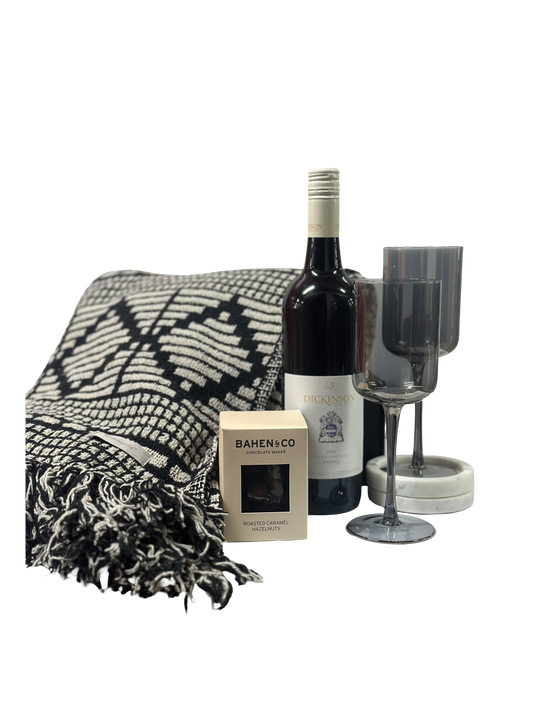 Wine bottle, two wine glasses, and a blanket on a white background