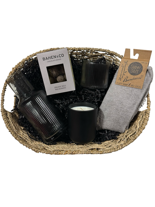 Gift basket with candles, a book, and socks on a white background