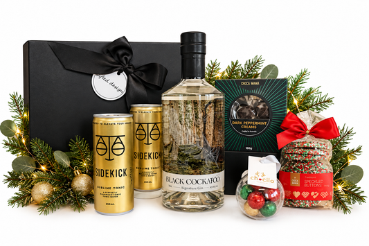 A stylish Christmas gift for those who appreciate quality gin, great taste and a little indulgence. Featuring Black Cockatoo Signature Gin, premium Sidekick tonics, Choca Mama dark peppermint creams and festive sweet treats.
Presented in a sophisticated black gift box and finished with luxurious ribbon, this gift brings together premium Australian spirits, artisan treats and festive flair — a fun yet refined choice for clients, colleagues or special celebrations.