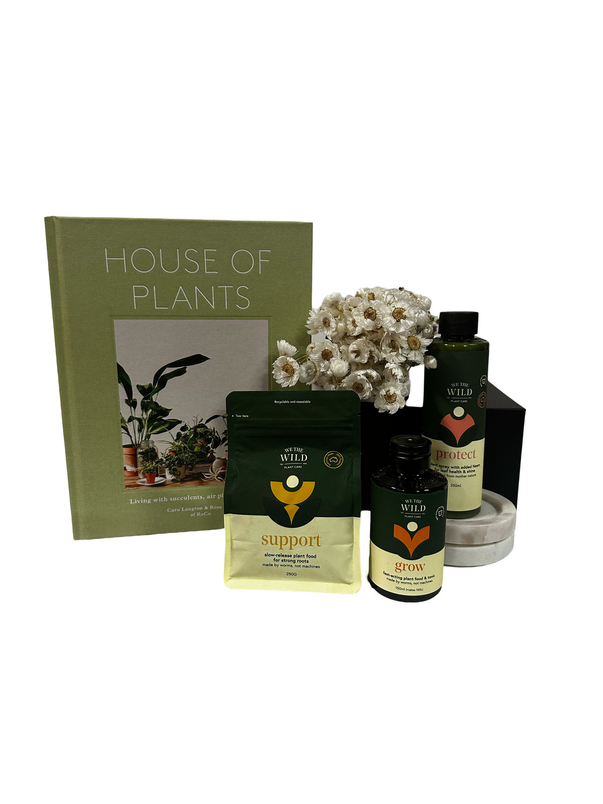 A gift set for plant lovers featuring a book titled 'HOUSE OF PLANTS', three bottles labeled and a vase with flowers, all presented on a matte surface.