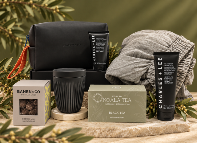 mens pamper gift with toiletry bag and toiletries , soft pants, cup, tea and treats on green background 