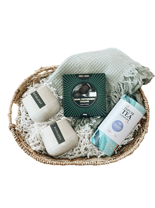Bowl with bath products including candles and a tea package on a white background