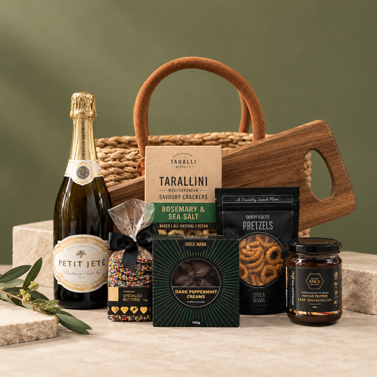 Gourmet gift basket with wine, snacks, and cheese on a green background
