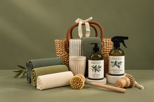 Woven basket with eco cleaning products, knit cloths, coffee cups, and wooden brushes.