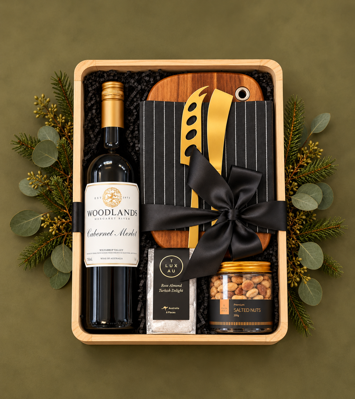A sophisticated gift celebrating great wine, beautiful design and relaxed entertaining. Featuring a Woodlands Margaret River Cabernet Merlot, a beautiful timber serving board, elegant gold cheese tools, a premium linen tea towel, artisan rose almond Turkish delight and gourmet salted nuts.
Presented in a natural timber gift box and finished with a luxurious black satin bow, this is a stylish and generous Christmas gift.
